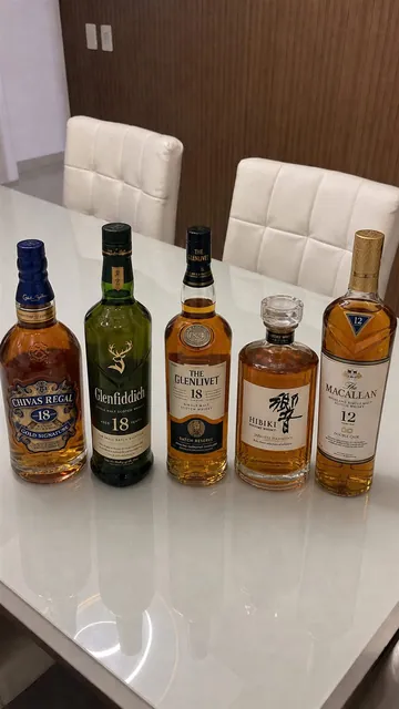 Five Pure Whisky bottles arranged on a glass table
